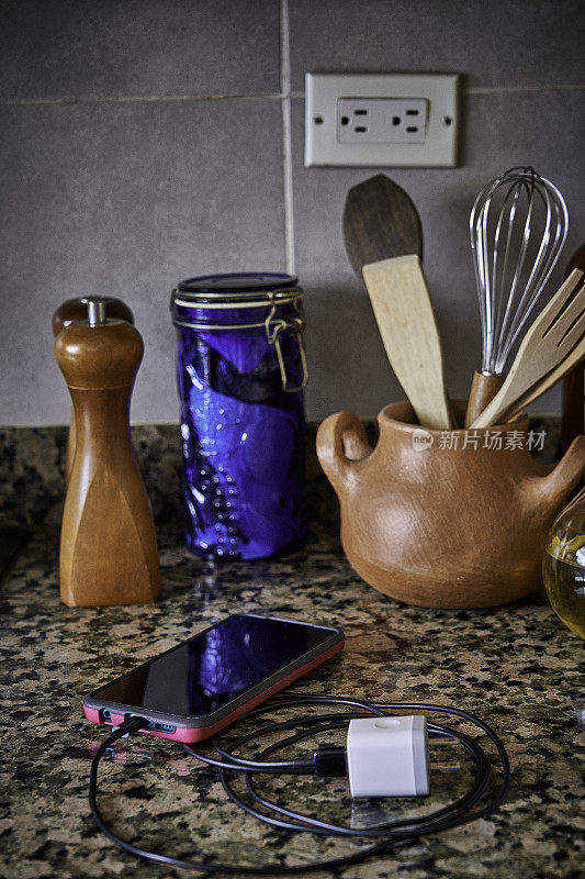 Charging power cable and power adaptor with smartphone on countertop in a domestic kitchen at home